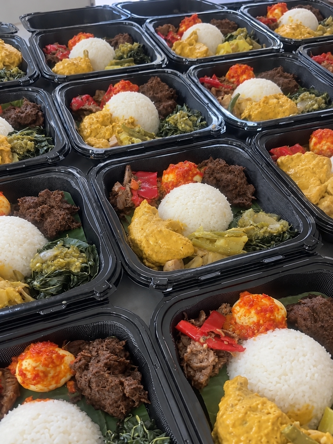 Nasi Padang meals with rice, beef, egg, curry, and vegetables in takeaway trays